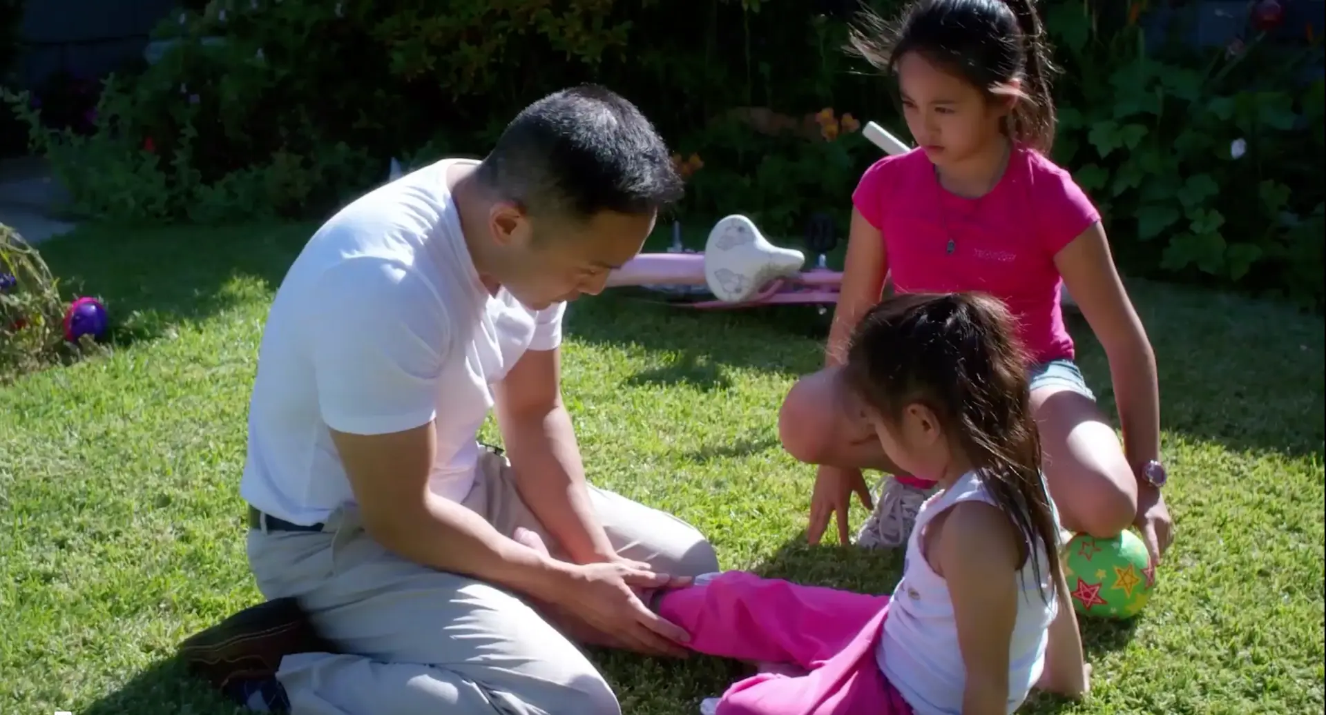 For Gina film still: a man and two girls sitting together in a sunny garden