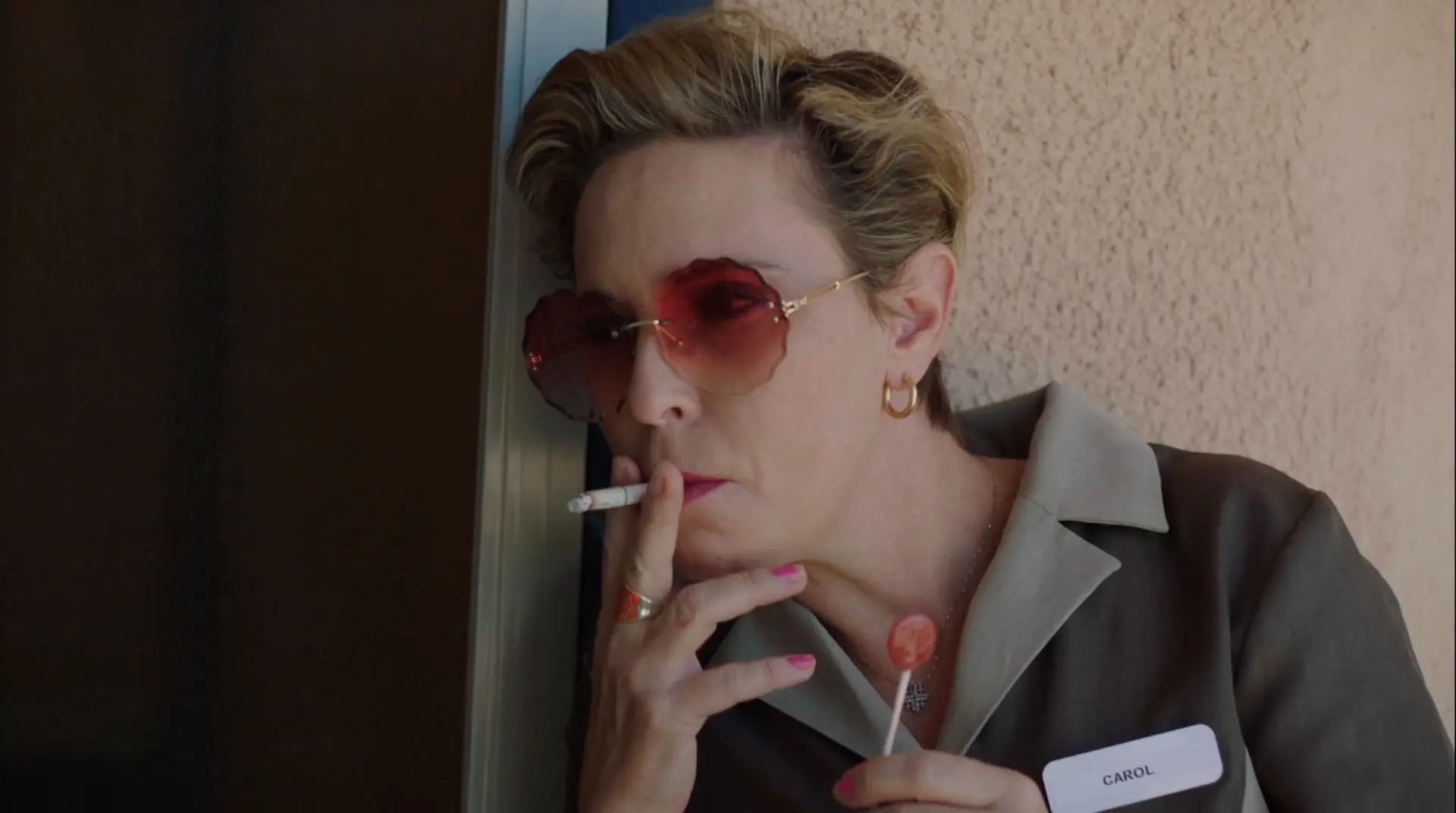 Coyote film still: a woman in red sunglasses holding a cigarette and a lollipop