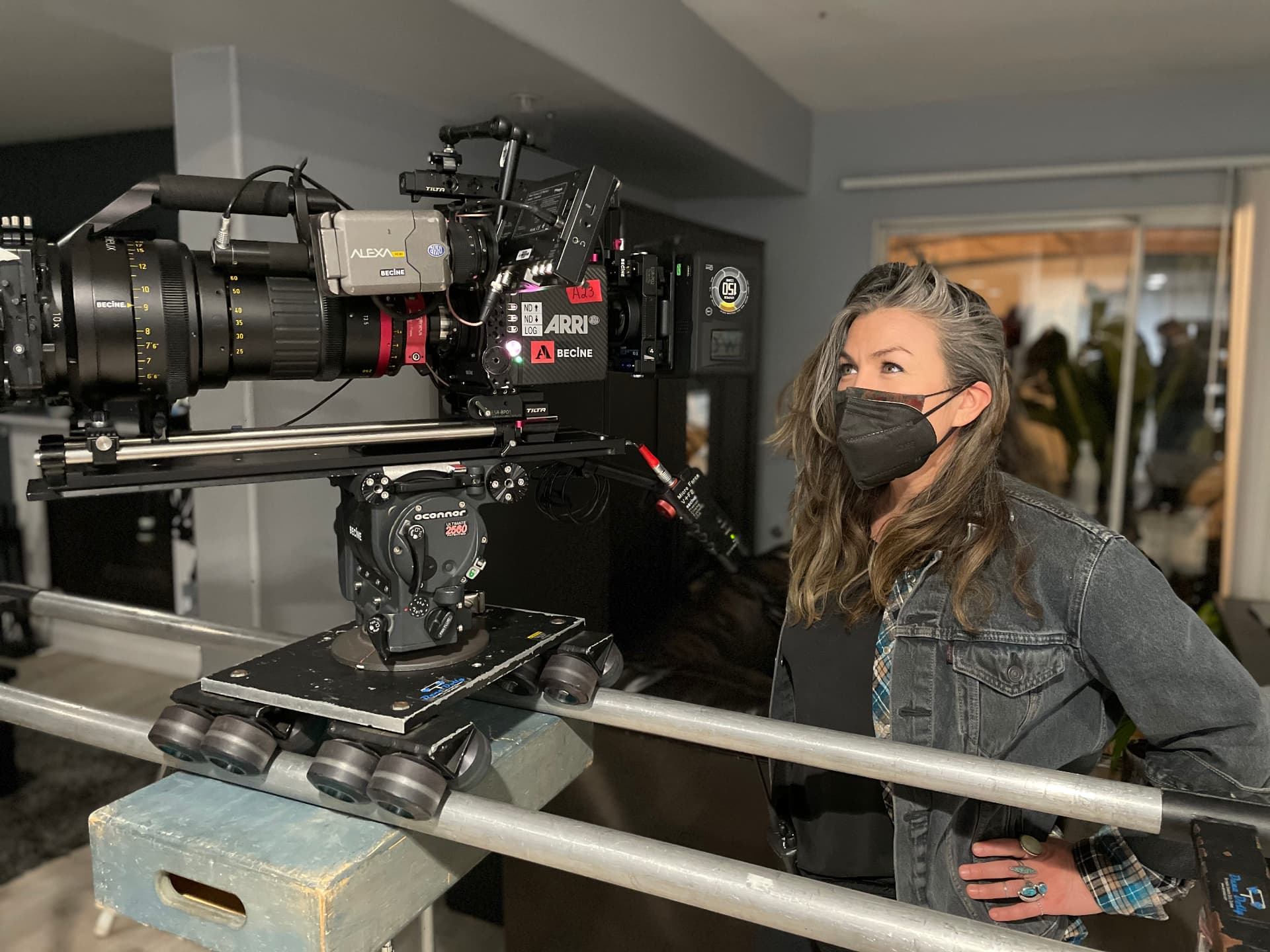 Rodes Phire wearing a black face mask beside an ARRI cinema camera on set