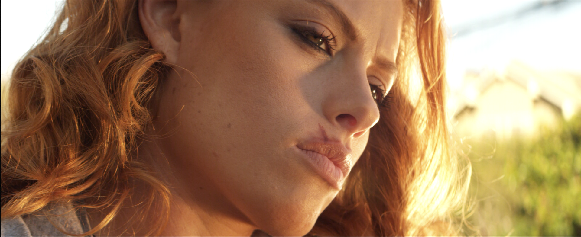 Followed film still: a close-up of a red-haired woman in warm sunlight