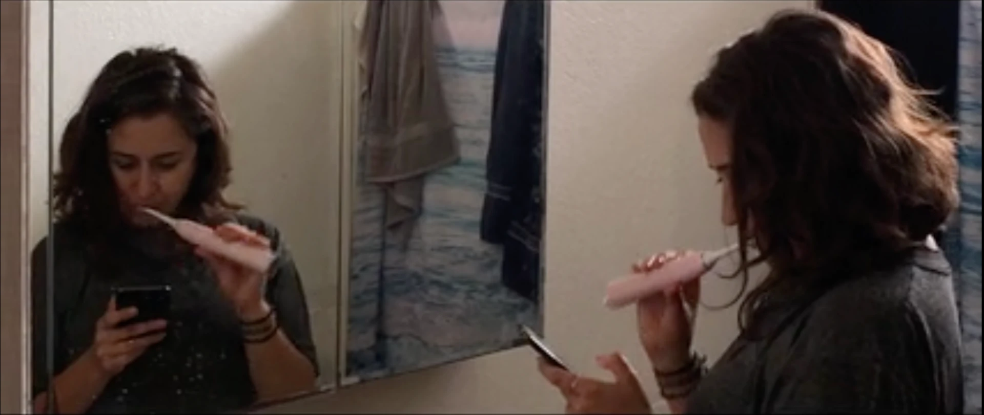 mindFULLness film still: a woman checking her phone while brushing her teeth in a bathroom mirror